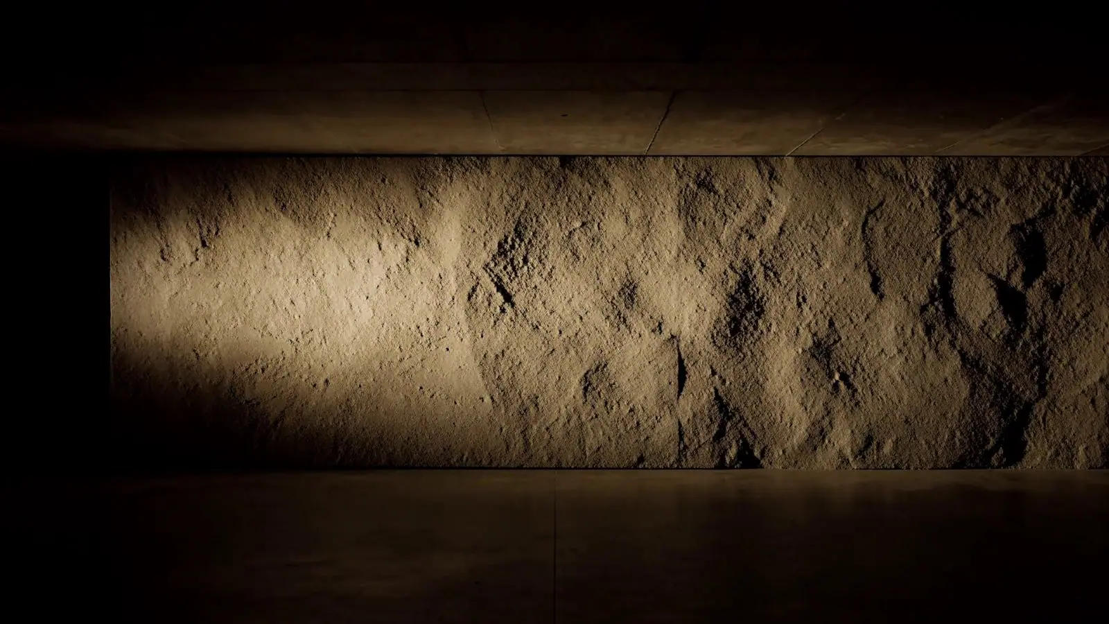 A beam of warm light crossing a dark concrete wall