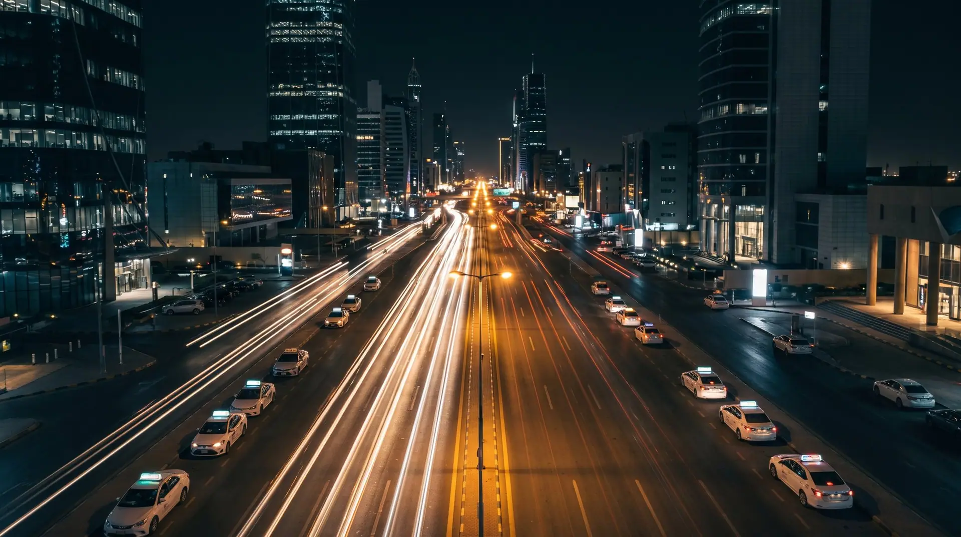 Aerial view of taxis with lit rooftop displays along a boulevard
