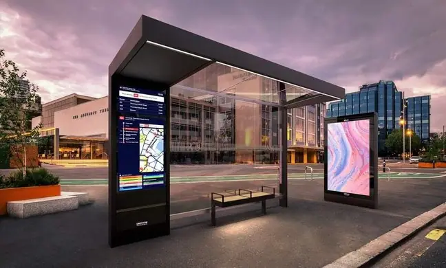 Bus shelter with integrated digital display at dusk