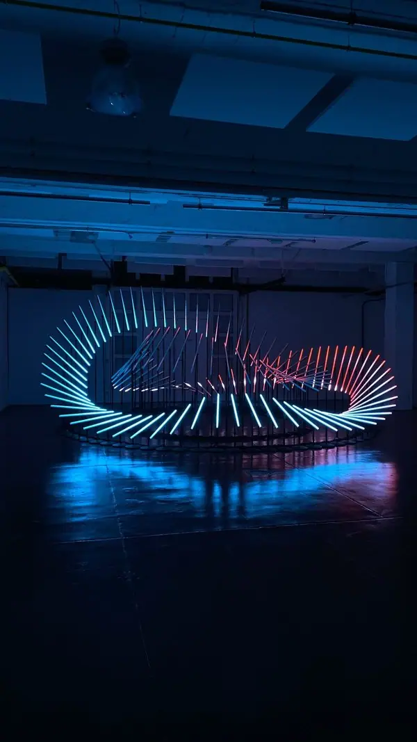 Illuminated ring sculpture beside a curved pool at night
